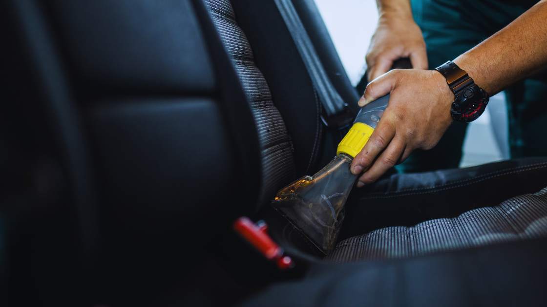 Une personne qui nettoie l'intérieur d'une voiture avec un aspirateur