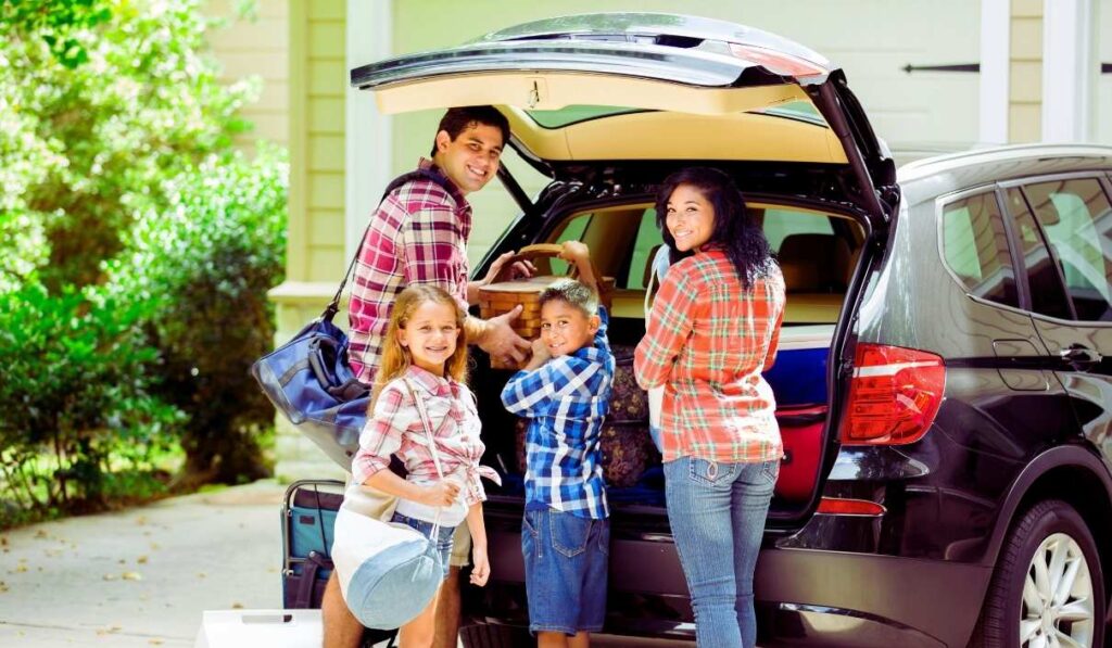 Une famille qui charge le coffre de sa voiture avant de partir en vacances