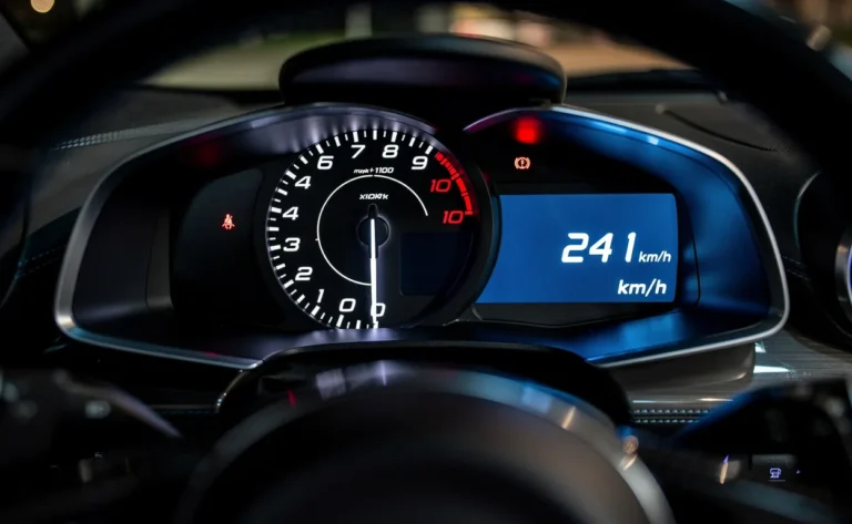 Un compteur de vitesse moderne dans une voiture de sport, aiguille à 150 mph et affichage numérique à 241 km/h, avec éclairage bleu sur le tableau de bord.