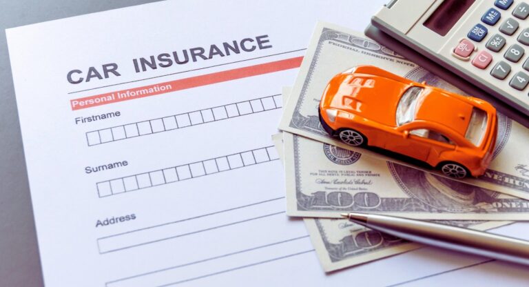 Formulaire d'assurance auto posé sur un bureau avec une voiture miniature, des billets et une calculatrice